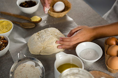 Close-up of woman preparing dough surrounded with various ingredients