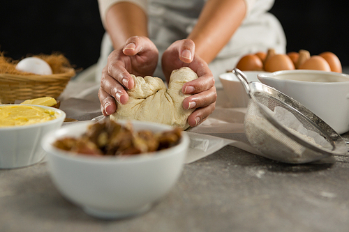 Close-up of woman preparing dough surrounded with various ingredients