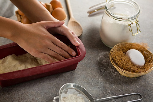 Close-up of woman preparing dough surrounded with various ingredients
