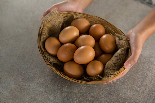 Close-up of woman holding basket with brown eggs