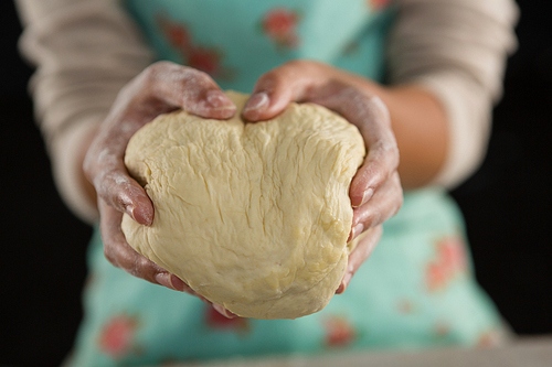 Mid-section of woman holding a dough