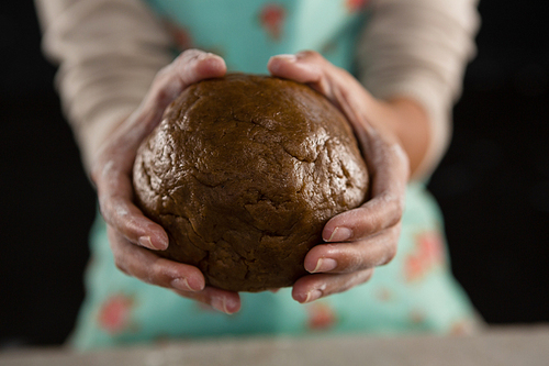 Mid-section of woman holding a dough