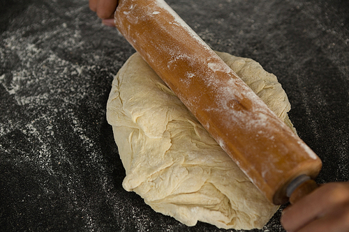 Close-up of hand baking dough with rolling pin