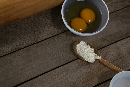 Close-up of egg yolk and flour in spoon on a wooden table