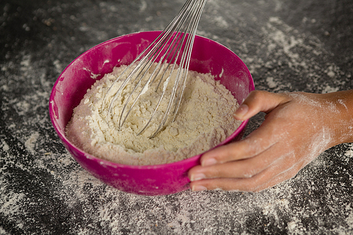 Close-up of woman whisking flour in bowl