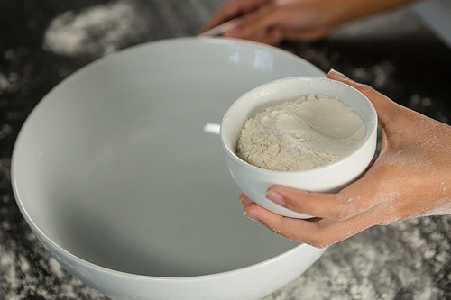 Close-up of woman holding bowl with flour