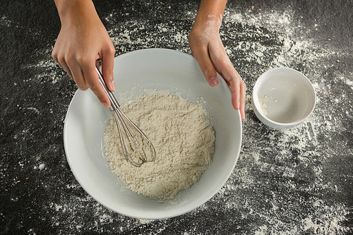 Close-up of woman whisking flour in bowl