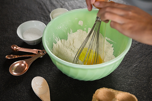 Close-up of woman whisking flour in bowl