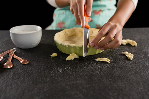 Close-up of woman slicing off extra dough from the mold