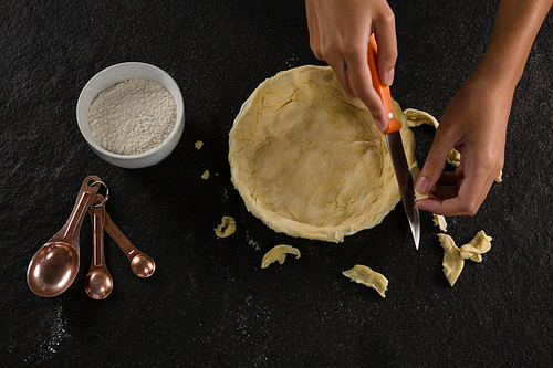 Close-up of woman slicing off extra dough from the mold