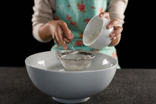 Mid section of woman sieving into the bowl