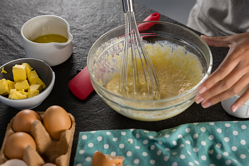 Close-up of woman whisking batter of beaten eggs and milk in a bowl