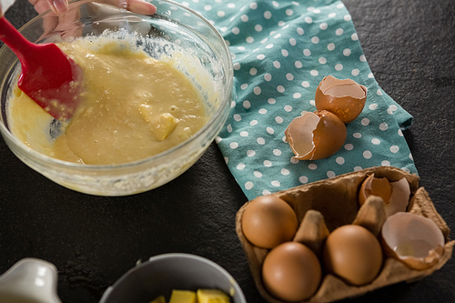 Close-up of woman mixing batter of beaten eggs, milk and butter in a bowl