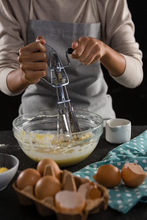 Mid section of woman whisking batter in a bowl