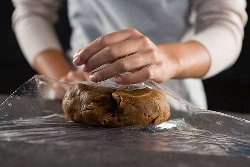 Mid section of woman wrapping dough in a plastic wrap