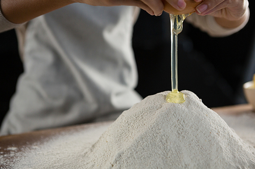 Close-up of woman adding egg white into flour
