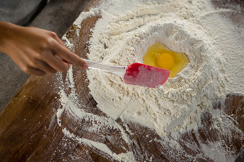 Over head view of woman mixing flour and egg with a batter spatula