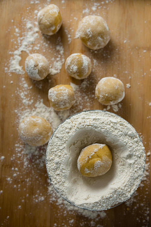 Over head view of dough ball placed over flour on a wooden table