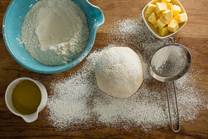 Over head view of flour sprinkled over dough on a wooden table