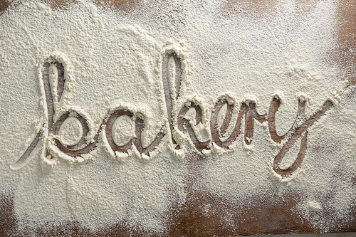 Close-up of the word bakery written on sprinkled flour