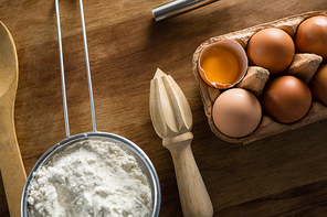 Over head view, flour, eggs and rolling pin placed over butter paper on a table