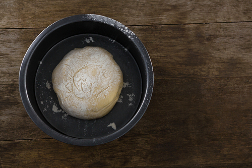 Over head view of kneaded dough placed in a bowl on a wooden table