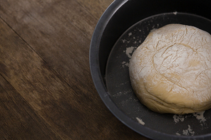 Close-up of kneaded dough placed in a bowl on a wooden table