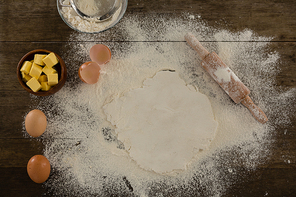 Over head view of flattened dough sprinkled with flour on a wooden table