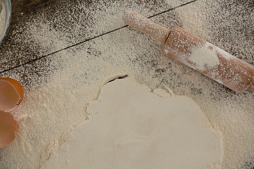 Close-up of flattened dough sprinkled with flour on a wooden table