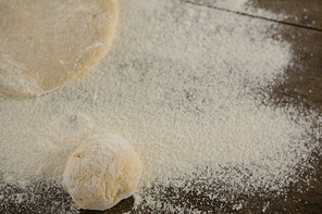 Over head view of flattened dough sprinkled with flour on a wooden table