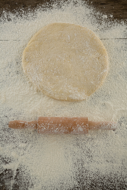 Over head view of flattened dough sprinkled with flour on a wooden table