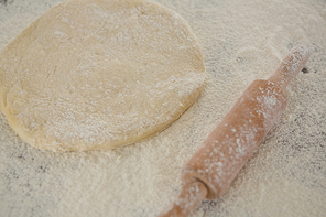 Close-up of flattened dough sprinkled with flour on a wooden table