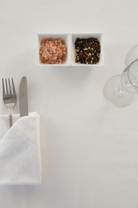 Fork, butter knife and spoon in napkin on white background