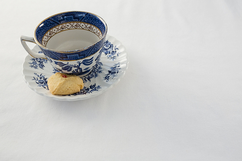 Empty cup with saucer and sweet food on white background