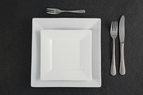 Close-up of square plates and cutlery set on a table