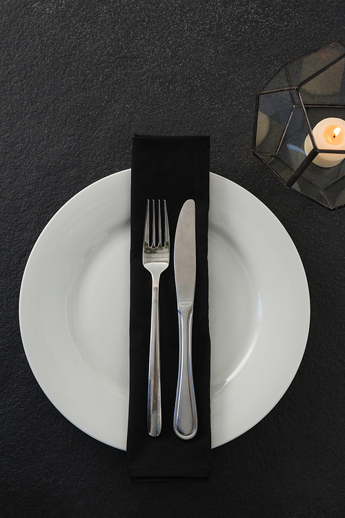 Close-up of table setting with lit candle