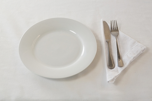 Close-up of plate, cutlery set and napkin on table
