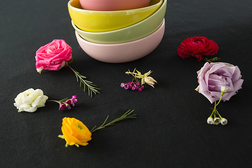 Close-up of bowls and flowers arranged on a black themed table
