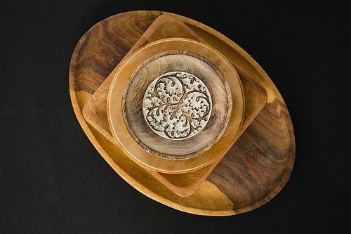 Overhead view of wooden plates set on a black theme table