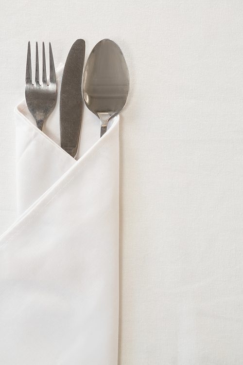 Close-up of spoon, knife and fork wrapped in a napkin