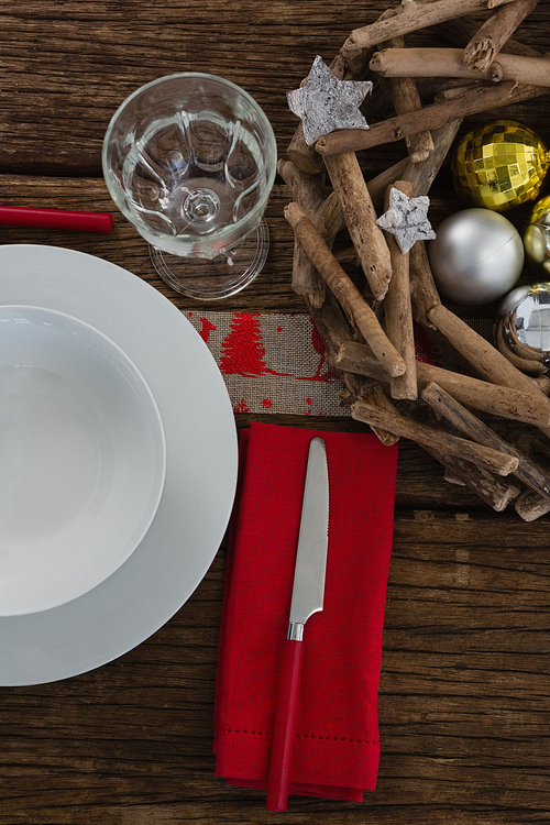 Overhead view of butter knife, napkin with plate, glass and christmas decoration