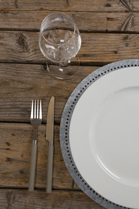 Overhead view of plate and wine glass with fork and butter knife on wooden table