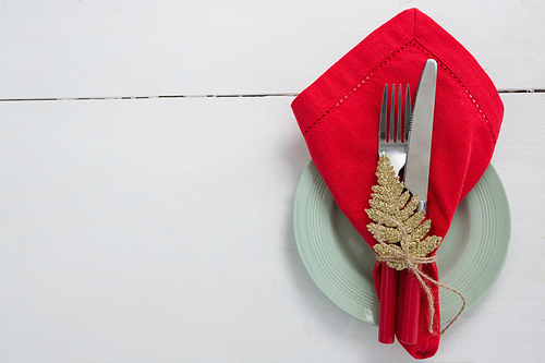 Overhead view of fork and butter knife with napkin and christmas ornament tied up with a rope
