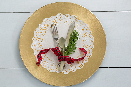 Overhead view of cutlery with fern tied up with ribbon on a placemat