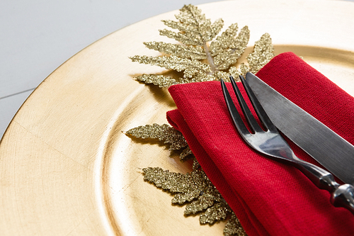 Close-up of cutlery with napkin and christmas decoration in a plate