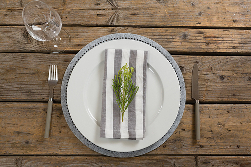 Overhead view of fork, butter knife and wine glass with napkin and herb in a plate