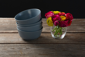 Close-up of stacked bowls and flowers on wooden plank