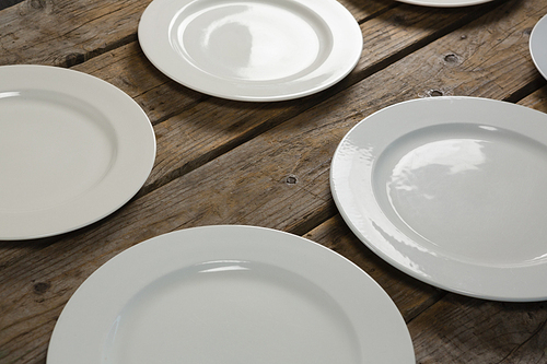Close-up of empty plates on wooden plank