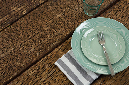 Overhead of plate with fork and napkin on wooden table