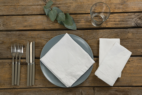 Plate with cutlery set and napkin on wooden table